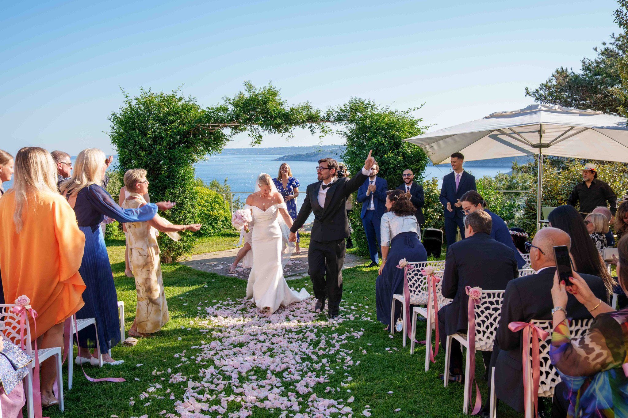 Los novios salen de la ceremonia entre los vítores de los invitados — boda internacional en Cala dei Balcani, Santa Cesarea Terme, Salento
